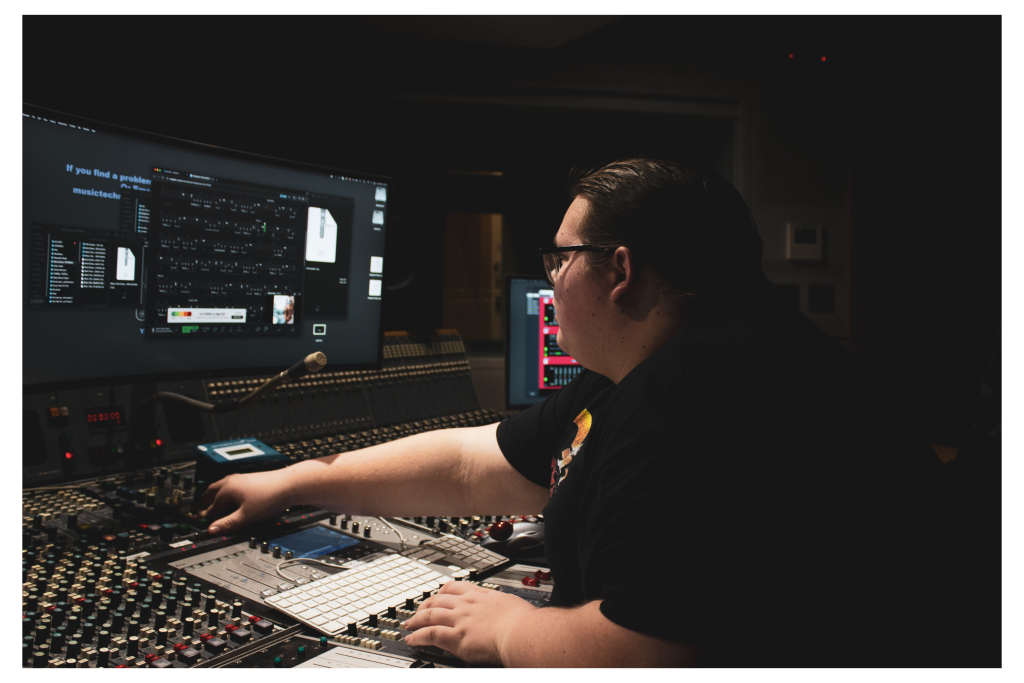 Owner, Jamie McCallum, sat reaching over a mixing desk.